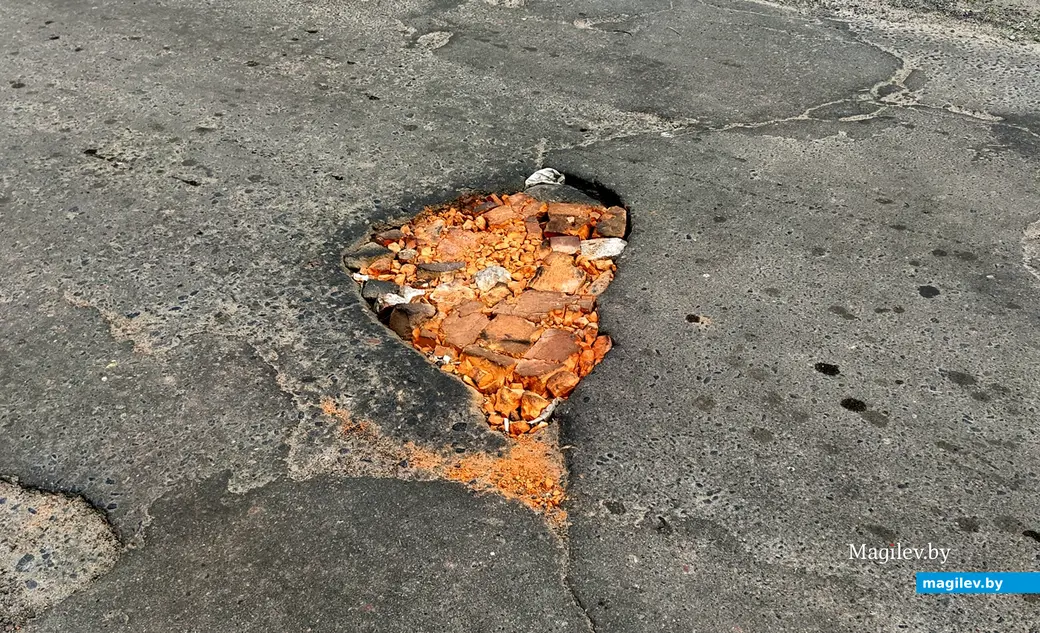 Яма на дороге во дворы проспекта Шмидта. Могилев, 10 июня, 2022 года.