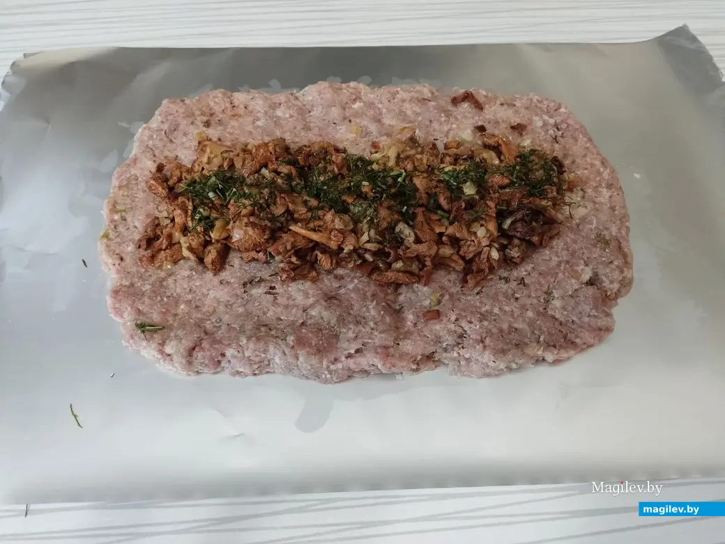 В середину мясного прямоугольника выложить начинку из грибов с луком