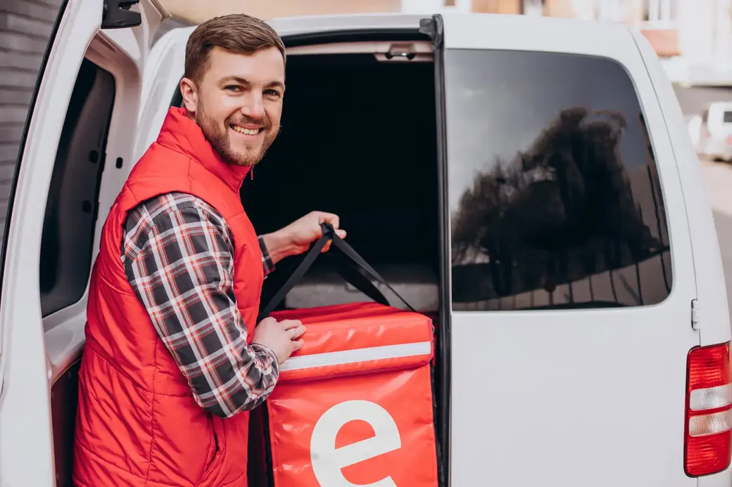 Food delivery man putting food box into a car