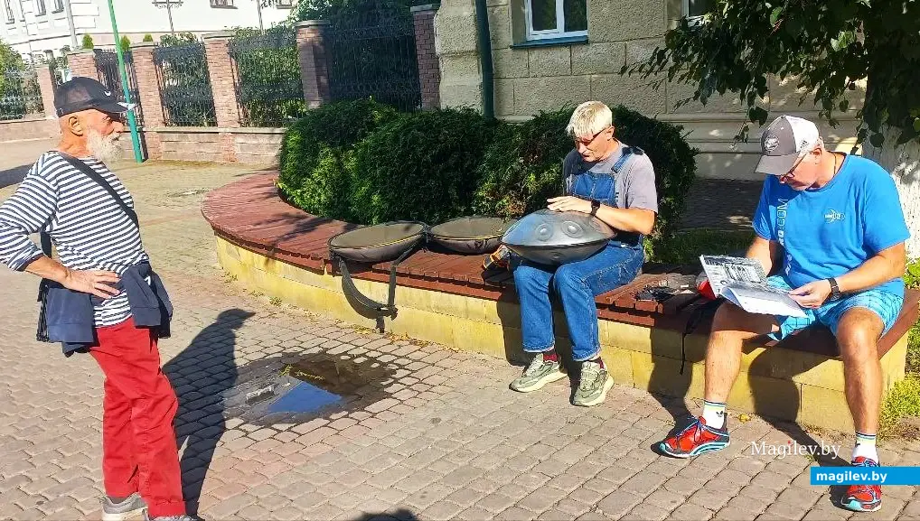 Август 2025 года, Могилев, ул. Ленинская. Борис Борщ слушает необычную музыку, а люди рассматривают альбом его живописных произведений.